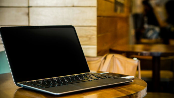 13 inch laptop open on wooden table in cafe setting