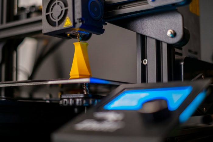 3D printer creating a yellow geometric model