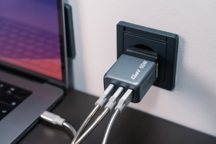 65W GaN charger plugged into wall with multiple cables