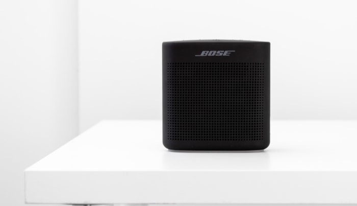 A black Bose portable speaker on a stark white shelf