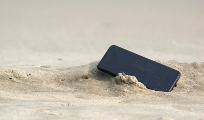 A black smartphone lay on sand