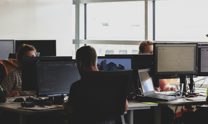 A busy tech office with professionals working on computers