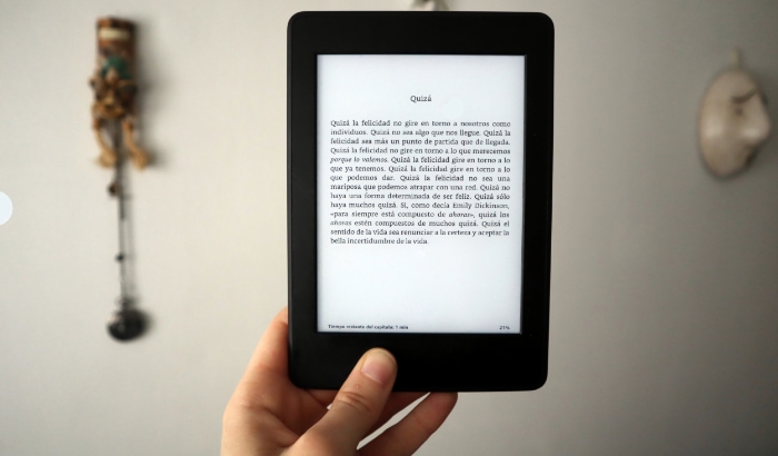 A hand holding a Kindle displaying text in Spanish