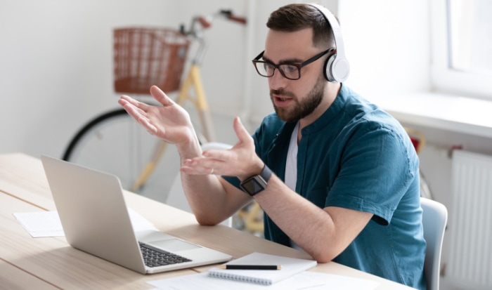 A man expressing a problem while using headphones and a laptop