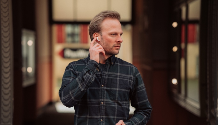 A man using AirPods while holding a phone