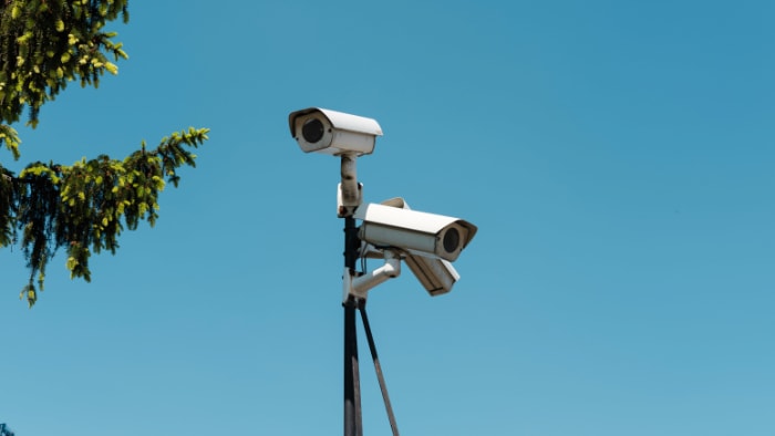 A pair of outdoor security cameras against a clear blue sky