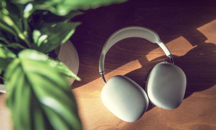 A pair of white headphones rests on a wooden table