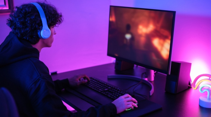 A person gaming in a room lit with purple ambient lighting