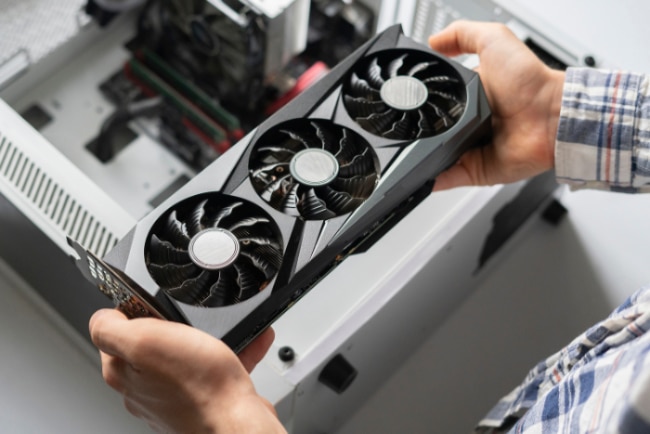 A person holding a graphics card with three fans