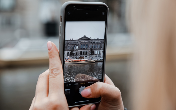 A persons hand holding a smartphone capturing a historical building