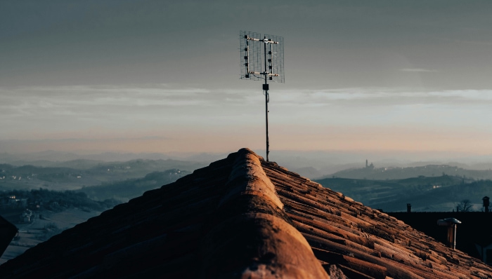 A rooftop antenna against a dusk sky