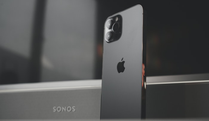 A space gray iPhone 11 Pro stands against a Sonos speaker