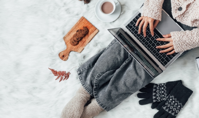 A woman with winter clothes working on laptop
