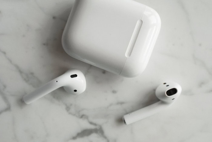 AirPods earbuds and charging case on marble surface