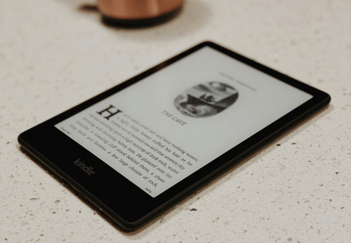 Amazon Kindle e reader on counter near copper mug