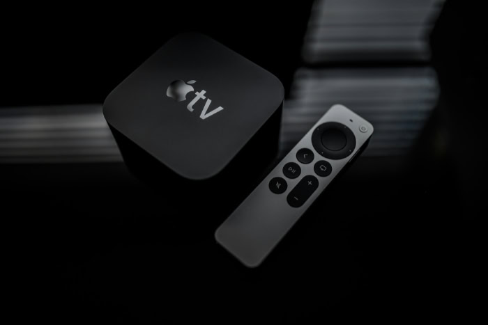 Apple TV 4K box and remote on reflective surface