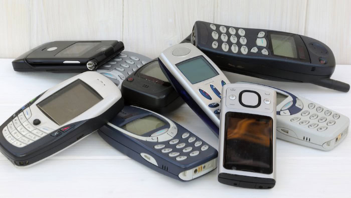 Assorted old burner phones on white surface