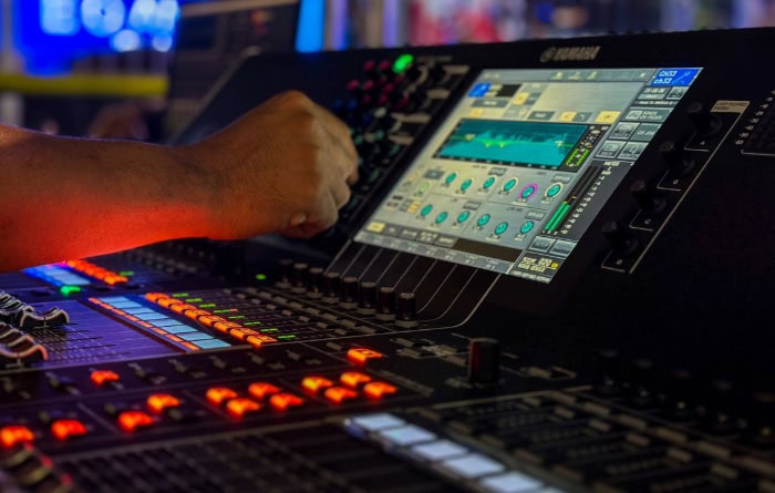 Audio engineer adjusting digital mixing console settings