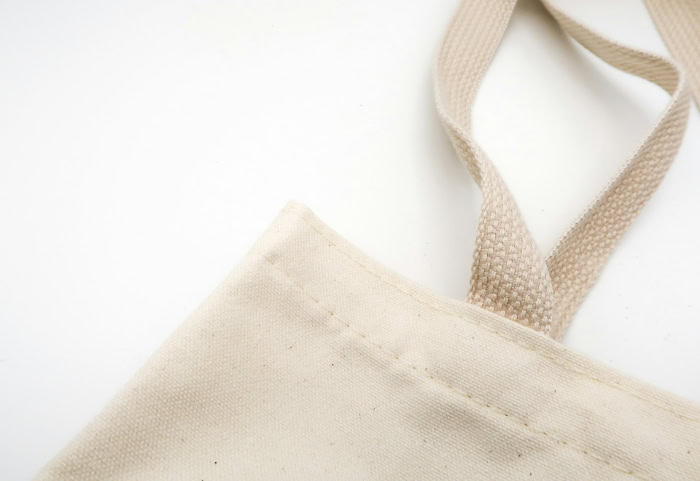 Beige canvas tote bag strap on white background