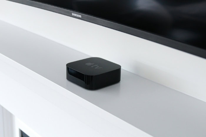 Black Apple TV box on white fireplace