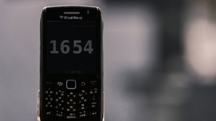 Black BlackBerry phone displaying time on screen closeup