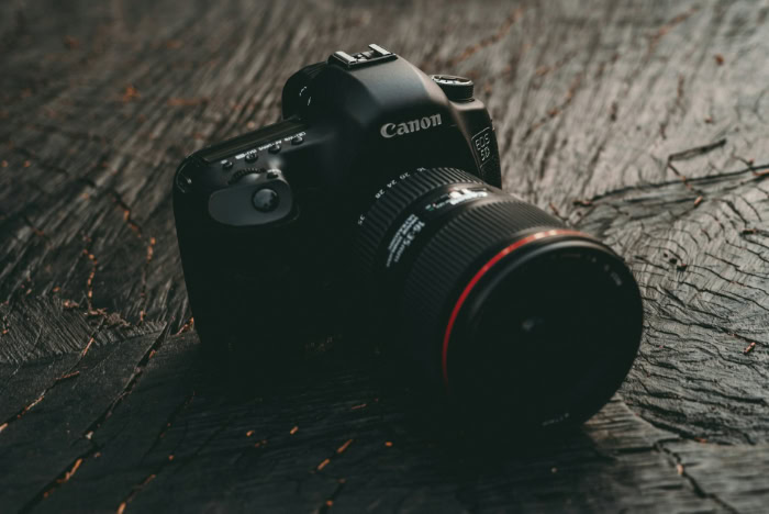 Black Canon DSLR camera on dark wooden surface