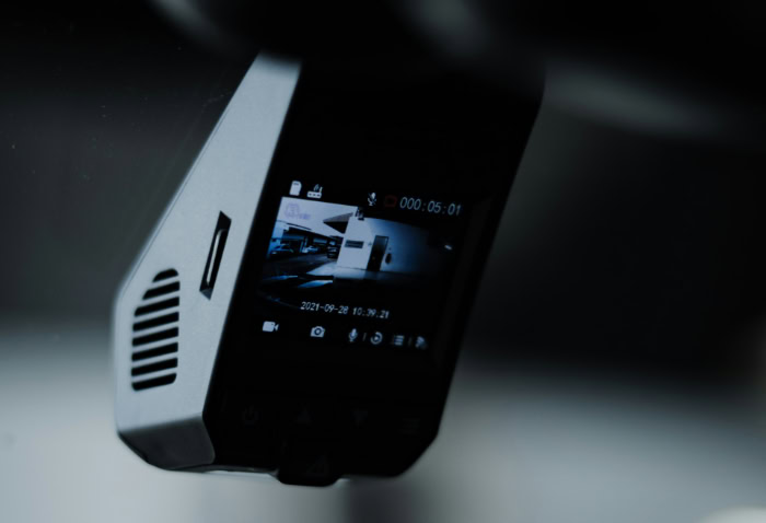 Black dashcam recording video mounted on car windshield