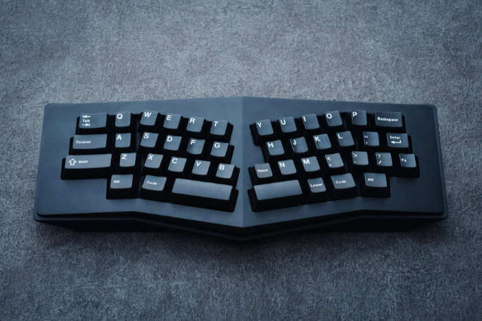 Black ergonomic mechanical keyboard on a grey textured surface