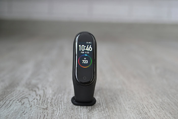Black fitness tracker standing upright on light wooden surface