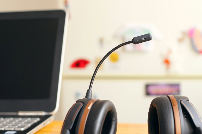 Black headset with microphone next to a laptop
