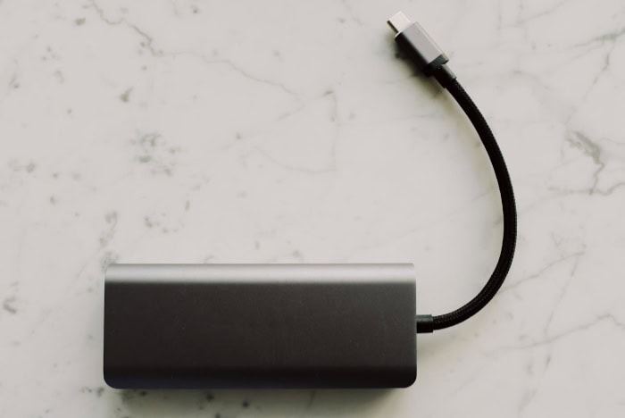 Black portable power bank with USB C cable on marble surface