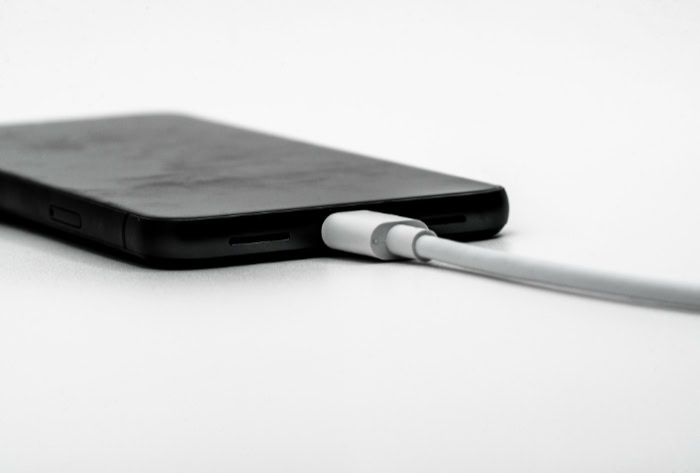 Black smartphone charging with a white cable