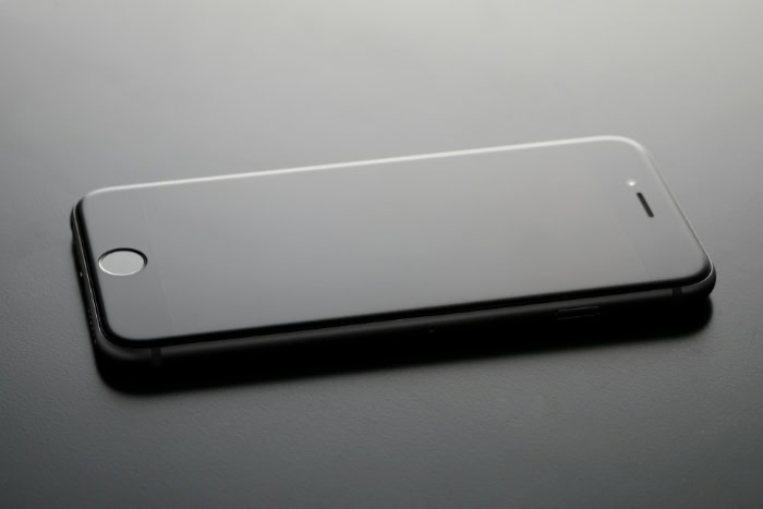 Black smartphone lying on a dark reflective surface
