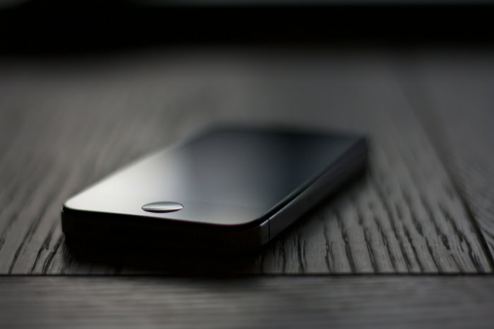 Black smartphone lying on a dark wooden surface