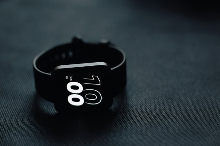 Black smartwatch displaying time on a dark surface