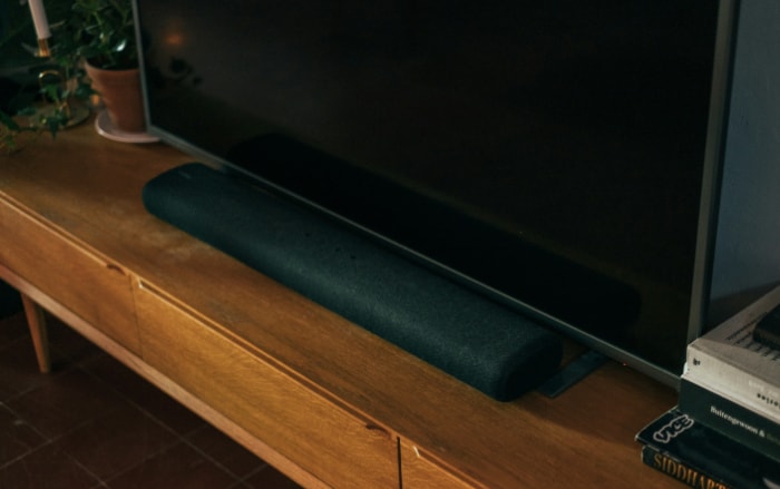 Black soundbar on wooden TV stand with plant decor
