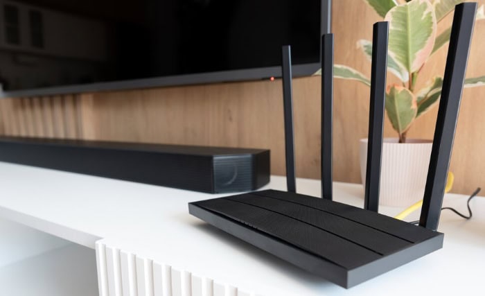 Black wireless router with antennas on white shelf