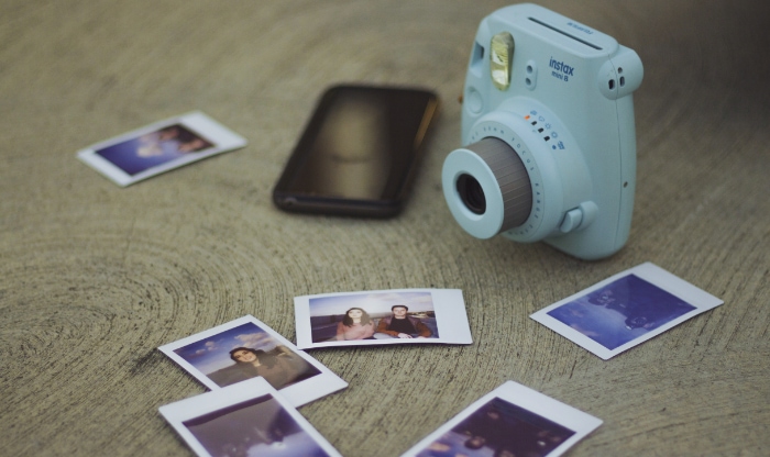 Blue instant camera near multiple photos film