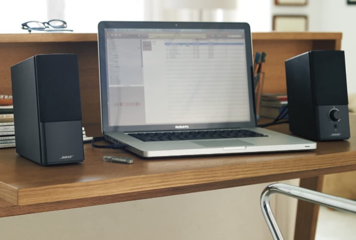 Black Bose Companion 2 Series III near Macbook Pro on wooden table