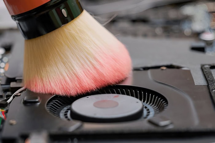 Brush cleaning dust from a laptop cooling fan