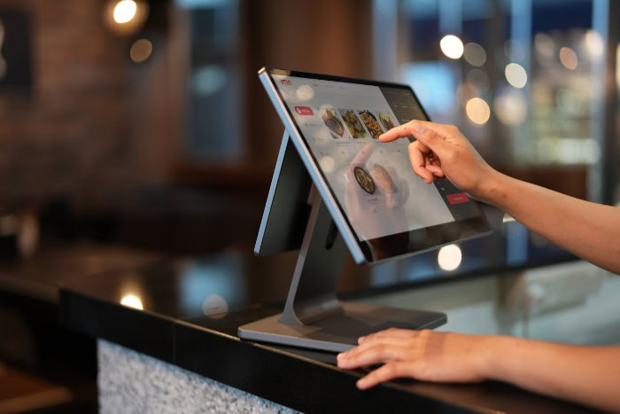 Cashier using touchscreen POS system at restaurant counter