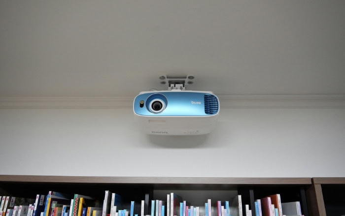 Ceiling mounted blue and white BenQ projector above bookshelf