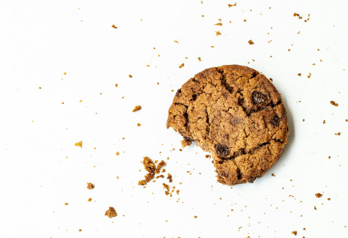 Chocolate chip cookie with crumbs on white background