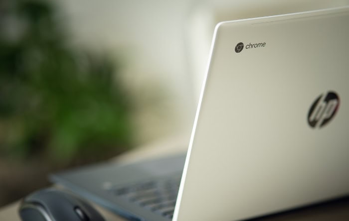 Close up of HP Chromebook with Chrome logo and computer mouse