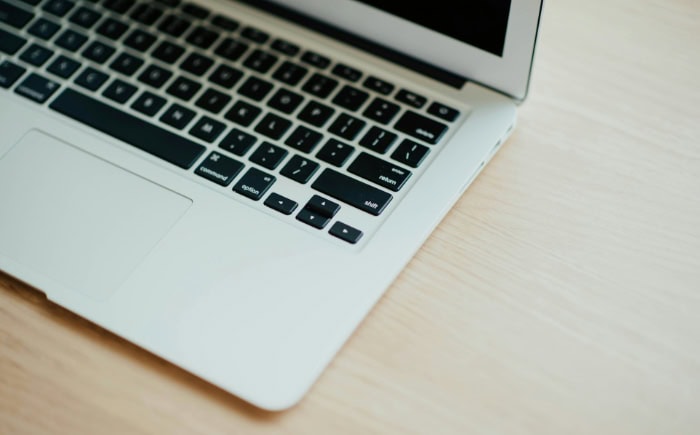 Close up of MacBook keyboard and trackpad on wooden surface