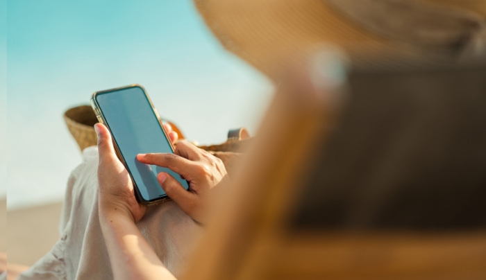 Close up of a person holding a smartphone with a straw hat