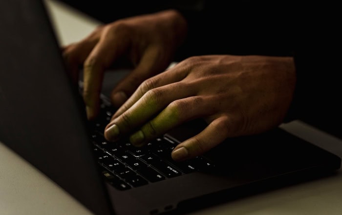 Close up of hands typing on laptop keyboard in dark