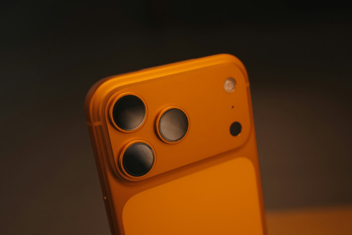 Close up of orange smartphone with triple camera lenses