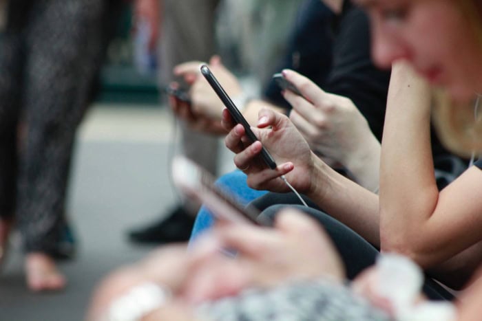 Close up of several people holding and using smartphones