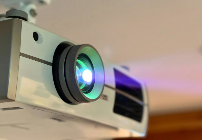 Close up of white projector lens emitting purple light